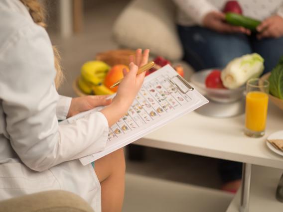 A dietitian in a white lab coat discusses a diet plan with a client.