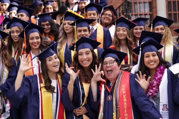 A crowd of graduate students pose in caps and gowns 